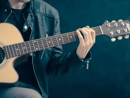 Mężczyzna w skórzanej kurtce gra na gitarze. Akordy układają się w piękną tonację d dur, tworząc melodyjną opowieść.