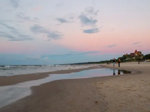 Zachód słońca nad morzem w Łebie. Piękne łeba atrakcje, plaża, zamek i spacerujący ludzie.