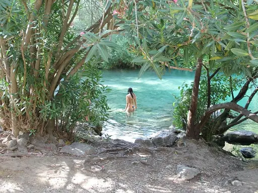 Una mujer se baña en la cueva del gato, un oasis de aguas cristalinas rodeado de vegetación exuberante.