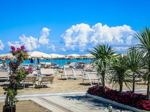 Spiaggia attrezzata con lettini e ombrelloni, palme e fiori colorati. Un'oasi di relax al Valentini Family Village, dove l'Hotel Rosalba vi aspetta.