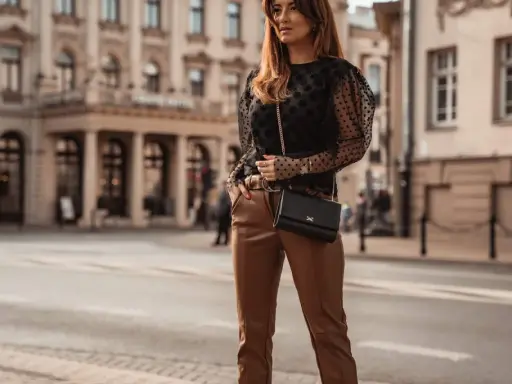 Elegancka stylizacja: czarna bluzka w kropki i brązowe skórzane spodnie. Idealne połączenie, by zadać pytanie: jaka bluzka do skórzanych spodni?