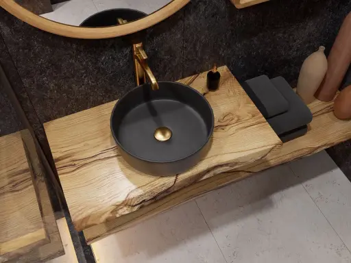 Złota bateria idealnie pasuje do czarnej umywalki nablatowej na drewnianym blacie.