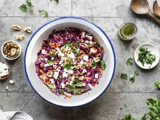 Frischer rotkohlsalat mit feta, karotten, walnüssen und Petersilie, bereit zum Servieren.