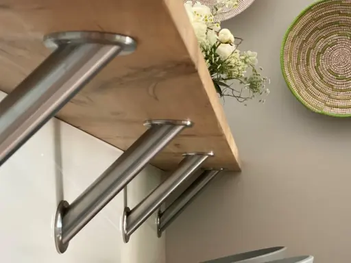 Stabile Metallwinkel befestigen die Holztheke auf der Arbeitsplatte. Ein Blumenstrauß ziert die Oberfläche.