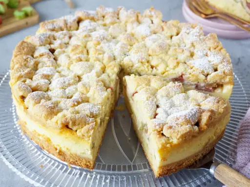 Saftiger Rhabarberkuchen mit Pudding und Streuseln, bestäubt mit Puderzucker. Ein köstlicher Genuss!