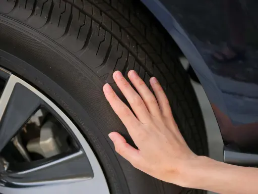 Una mano toca la banda de rodadura de un neumático, sugiriendo la pregunta de cuánto duran las ruedas de un coche.