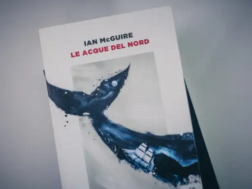 Copertina del libro "Le acque del nord" di Ian McGuire, con un veliero che naviga tra le onde scure e la coda di una balena.