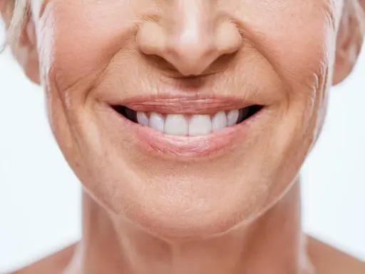 Sonrisa de mujer con piel madura, mostrando cómo disimular el surco nasogeniano con técnicas de maquillaje y cuidado facial.