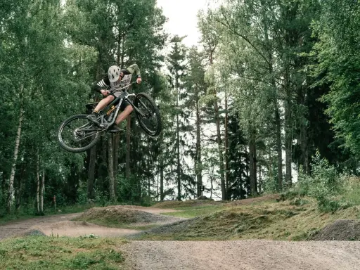 Mountainbike-åkare flyger genom luften i en skogspark nära Stockholm.