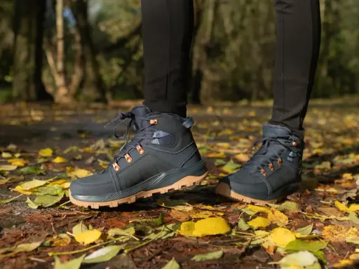 Jesienne buty trekkingowe na tle liści. Idealne, by dowiedzieć się, jak się ubrać w góry jesienią.