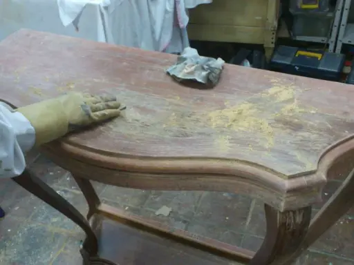 Proceso de como decapar un mueble antiguo, lijando la superficie para eliminar la pintura vieja.