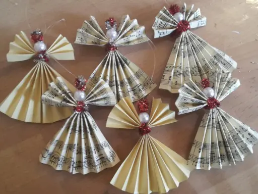 Selbstgemachter Christbaumschmuck: Kleine Weihnachtsengel aus Notenpapier und Perlen, die zum Basteln einladen.