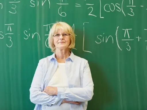 Nauczycielka matematyki przed tablicą z równaniami. Czy doczekamy się wcześniejszych emerytur dla nauczycieli?
