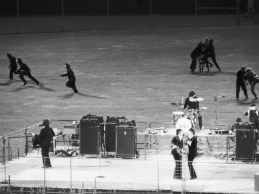 En kaotisk scen med figurer som springer, kanske en representation av The Beatles sista spelning.