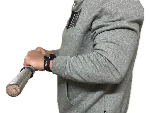 Person in grauem Hoodie macht einen Wrist Curl mit einer Hantel.