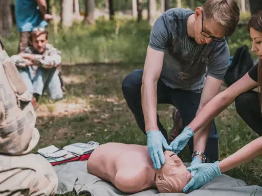 Uczestnicy kursu przetrwania ćwiczą resuscytację na fantomie w lesie.