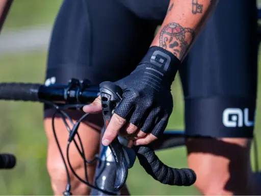 Rowerzysta w czarnych, bezpalczastych rękawiczkach, idealnych na rower, trzyma kierownicę.