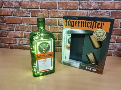 Butelka Jägermeistera z lampkami i zestawem kieliszków. Poznaj, jak smakuje jagermeister – ziołowy eliksir.