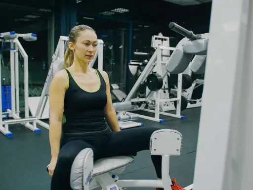 Frau trainiert ihre Adduktoren an einem Fitnessgerät im Studio.