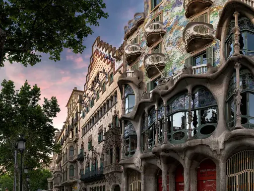 Casa Batlló in Barcelona, ein Meisterwerk des Art Nouveau, mit seinen organischen Formen und bunten Mosaiken, unter einem rosafarbenen Himmel.