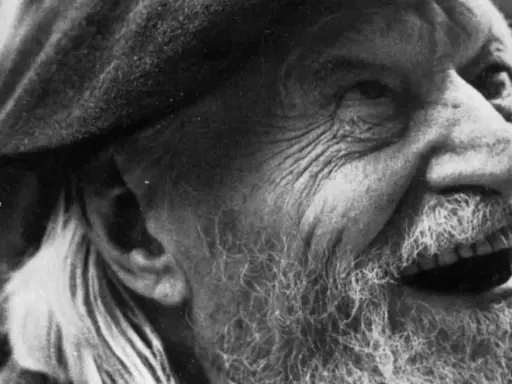 Primo piano di un uomo anziano con barba e cappello, il volto segnato dal tempo, come in un "giorno per giorno Ungaretti".