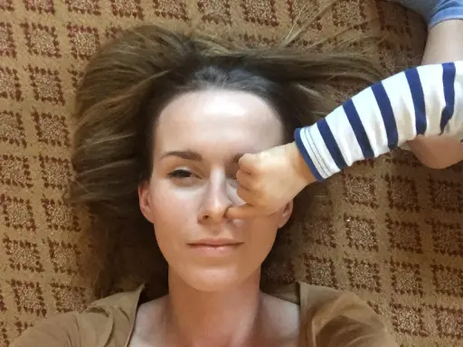 Kiedy mam dość swojego dziecka, jego rączka w paski zasłania mi oko. Leżymy na dywanie.