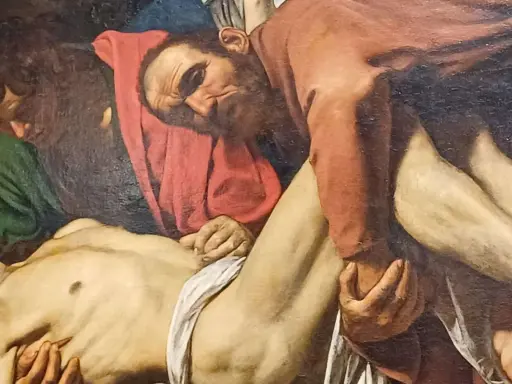 Détail de la mise au tombeau par Caravage : des hommes portent le corps du Christ, le visage marqué par la douleur.