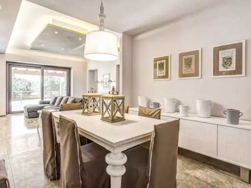 Un'elegante casa stile shabby chic moderno con tavolo da pranzo, divano e quadri botanici.