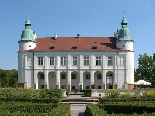 Baranów Sandomierski atrakcje: Zamek z arkadowym podcieniem i zielonymi wieżyczkami, otoczony zadbanym ogrodem.
