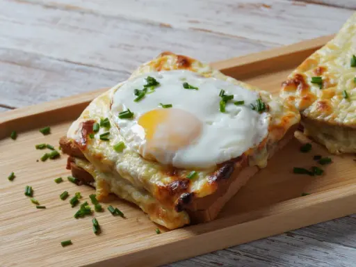 Croque monsieur con huevo frito y cebollino, un delicioso sándwich gratinado.