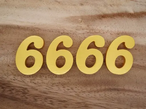 Quatre chiffres dorés 6666 sur fond de bois. Le 6666 signification est souvent lié à l'abondance et à la prospérité.