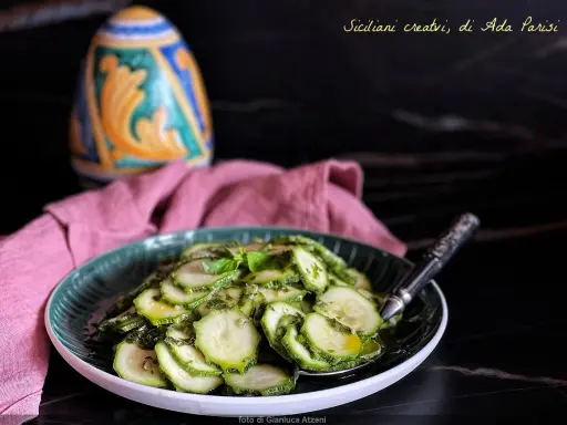 Fette di zucchine marinate crude, condite con erbe aromatiche e olio. Un contorno fresco e leggero, perfetto per l'estate.
