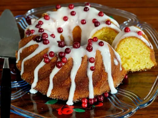 En saftig sockerkaka med vit glasyr och röda lingon, en perfekt höstkaka.