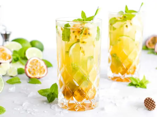Zwei erfrischende Passion Fruit Mojitos mit Minze und Limette, umgeben von frischen Früchten und Eis.