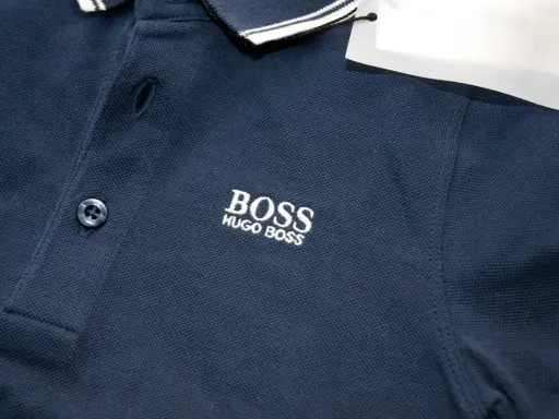 Granatowa koszulka polo z haftowanym logo BOSS HUGO BOSS. Widoczna oryginalna metka Hugo Boss.