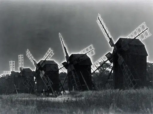 Mulini a vento in un campo, con un effetto di solarizzazione man ray che illumina le pale.