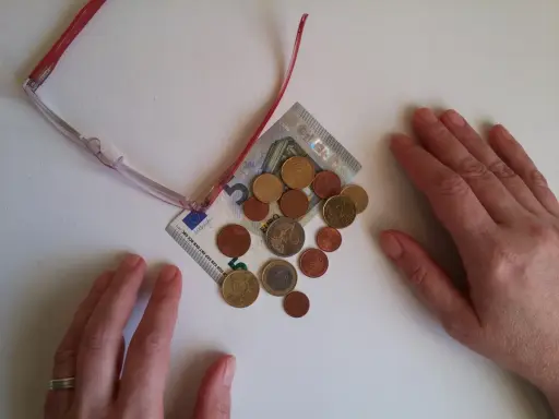 Manos sobre billetes y monedas, sugiriendo aportaciones a planes de pensiones IRPF.