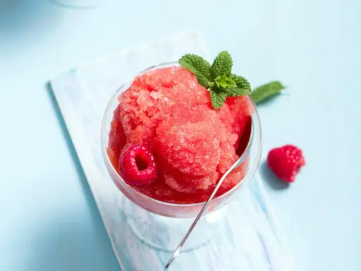 Erfrischendes Slush Eis mit Himbeeren und Minze in einem Glas, bereit zum Genießen.
