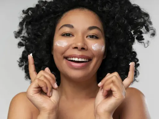 Donna sorridente con crema sul viso. La crema è non comedogeno, significa che non ostruisce i pori.