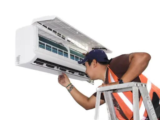Un technicien vérifie un climatiseur mobile qui ne refroidit plus. Il est sur une échelle, examinant l'appareil.