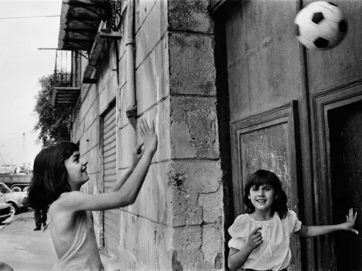 Bambine giocano a pallone in strada, un momento catturato da una fotografa famosa italiana.