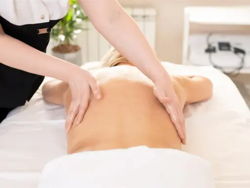 Relaksacyjny masaż kręgosłupa wykonany dłońmi terapeuty. Skóra lśni od olejku, a ruchy dłoni przynoszą ulgę.