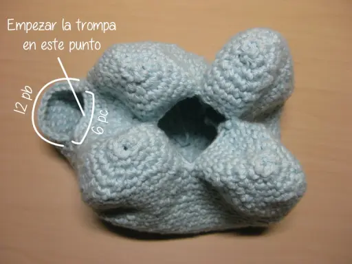 Un elefante amigurumi azul claro, en proceso de tejido. Se indica dónde empezar la trompa.