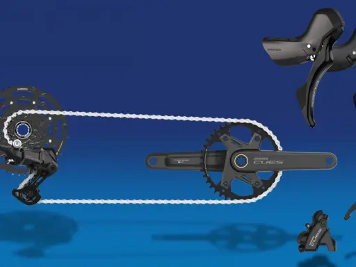 Shimano CUES Fahrradkomponenten: Schaltwerk, Kassette, Kurbelgarnitur und Schalthebel in Schwarz vor blauem Hintergrund.
