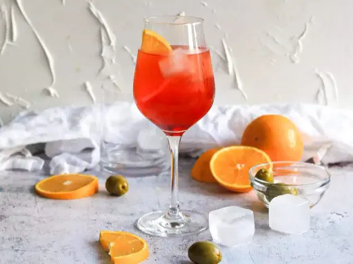 Ein Aperol Spritz mit Orangenscheibe und Eis. Orangen, Oliven und Eiswürfel deuten auf Aperol Spritz Varianten hin.