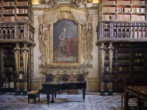 Prachtvolle Coimbra Bibliothek mit einem Flügel und einem Porträt.