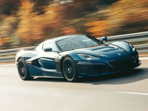 Blauer Rimac Nevera rast auf einer Straße, die Bäume im Hintergrund verschwimmen. Ein Beweis für die unglaubliche rimac nevera top speed.