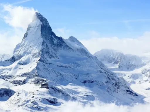 Majestatyczny, ośnieżony szczyt Matterhorn, jeden z najwyższych szczytów Europy, wyłania się z chmur.