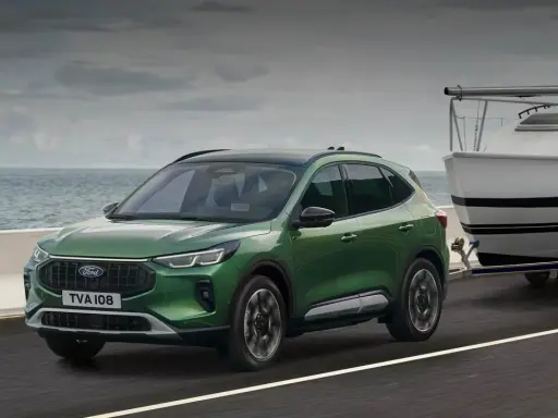 Zielony Ford Kuga z przyczepą i łodzią, idealny na wakacyjne wyjazdy. Sprawdź ford kuga cena!