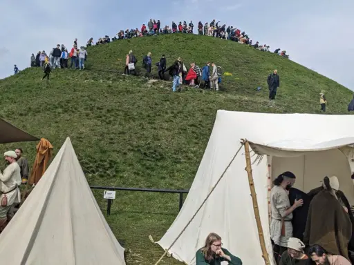 Ludzie wchodzą na Kopiec Kraka, a u jego podnóża rozstawiono historyczne namioty.